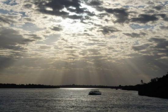 Sunset begins over the Zambezi with another boat visible in the foreground.