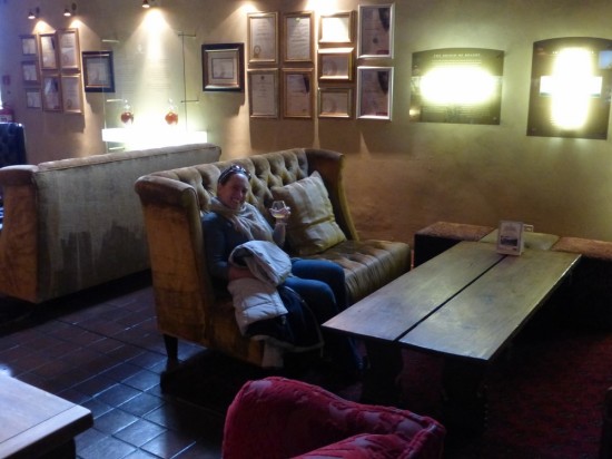 Danielle doing her best to fit in, sipping brandy and sitting in a leather-backed chair.